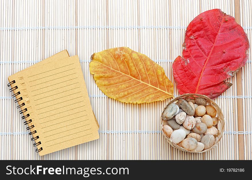 Brown notebook with line over wooden plate and dry leaf red and yellow