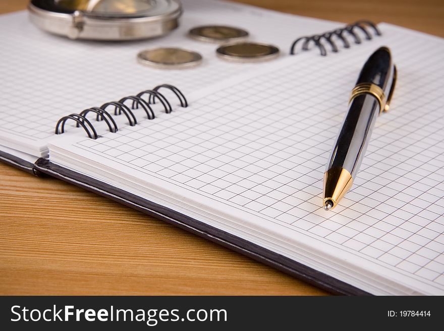 Silver compass and pen at notebook on wooden background