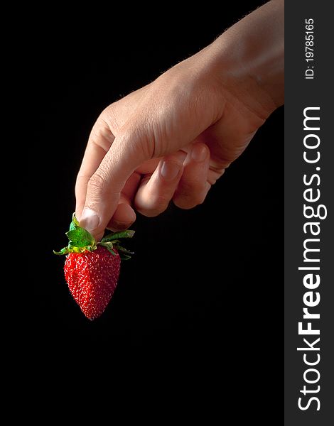 Hand with red strawberry isolated on black. Hand with red strawberry isolated on black