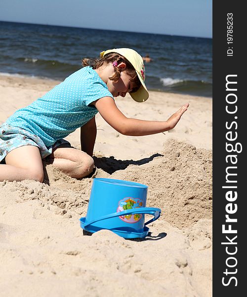 A girl sits by the sea and the sand castle building. A girl sits by the sea and the sand castle building