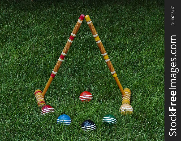 Striped croquet balls and mallets on green grass