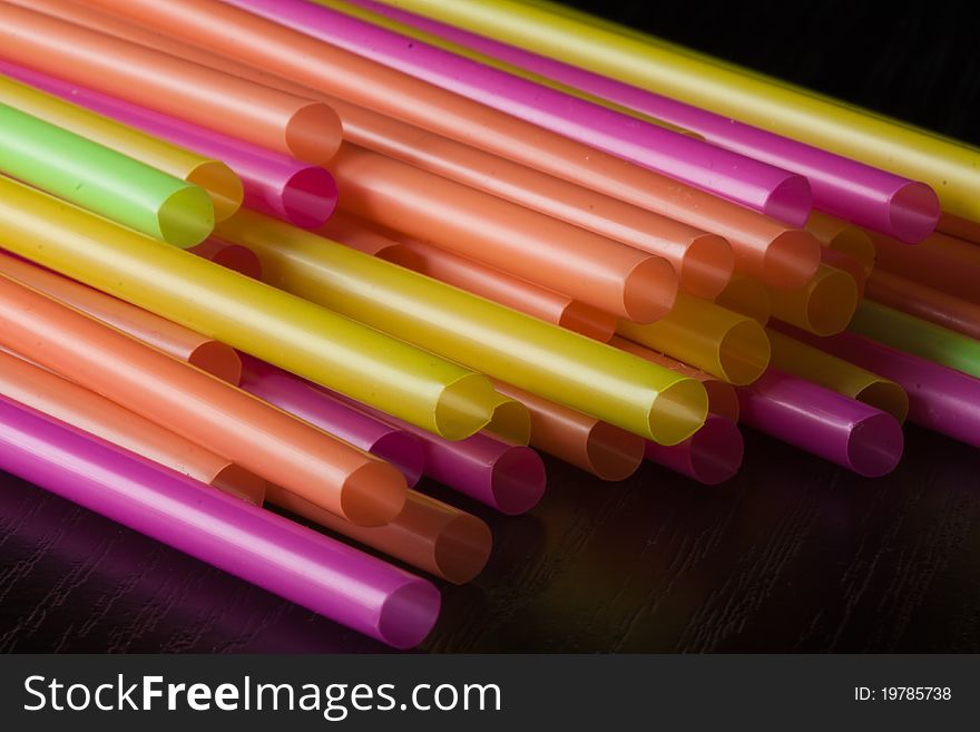 Bunch of colourful plastic straws in black background