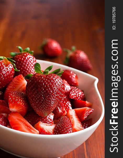 A bowl full of fresh strawberries, cut into pieces