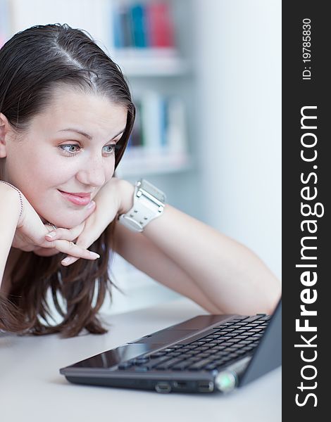 In the library - pretty female student with laptop and books working in a high school library (color toned image)