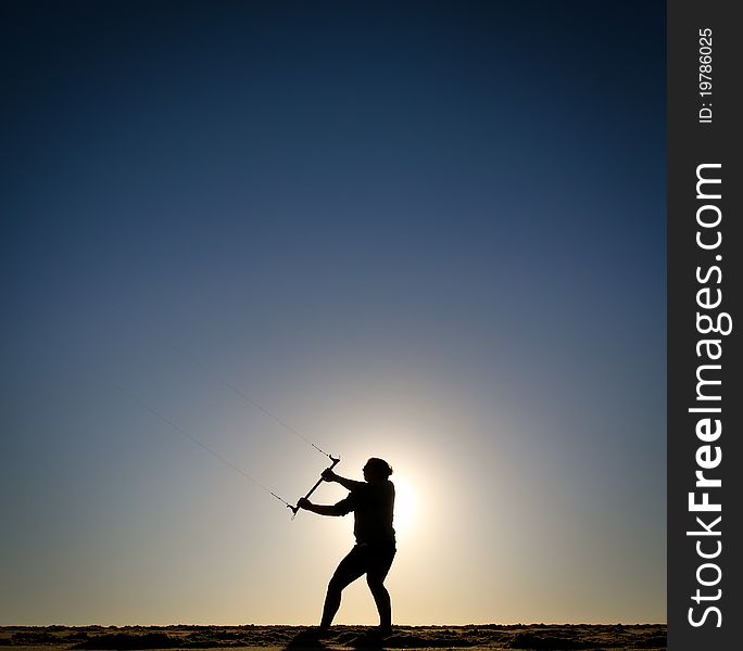 Silhouette of girl flying kite at sunset at beach