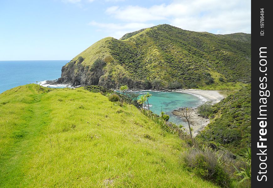 A little beach with pristine water surrounded by green mountains and vegetation. A little beach with pristine water surrounded by green mountains and vegetation