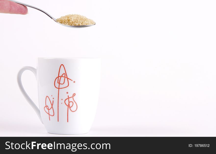 Teaspoon of raw sugar over a mug