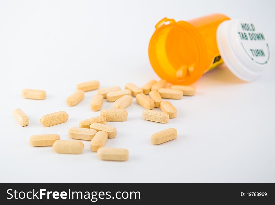 The photo of open pillbox with medicine spilling out isolated on white background