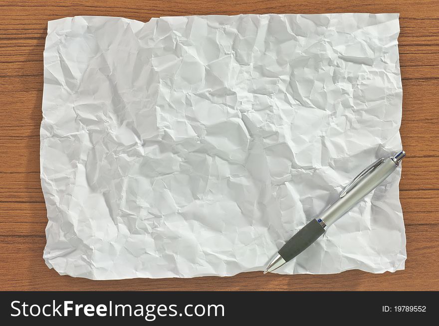 Crumpled blank paper with pen on wood table