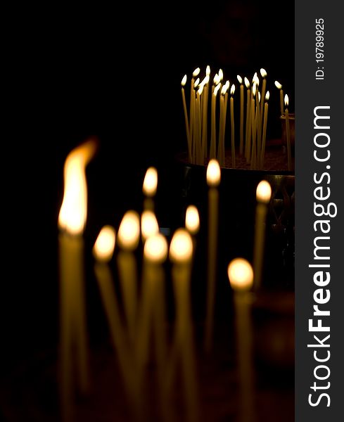 Burning votive candles in a Greek church over dark background. Burning votive candles in a Greek church over dark background.