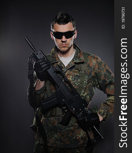 Young soldier in camouflage and ammunition with a gun. studio shot. Young soldier in camouflage and ammunition with a gun. studio shot