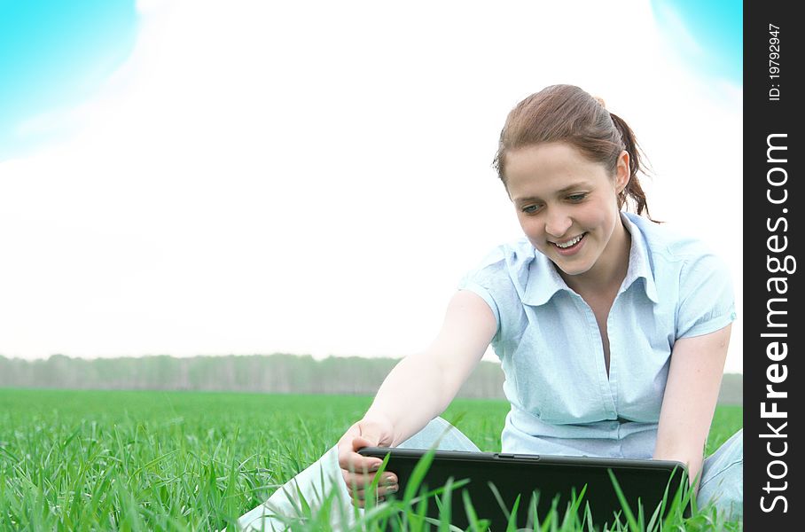 Girl sitting in the grass with laptop