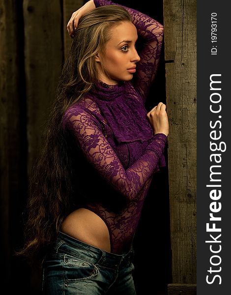 Fashion photo of young sensual woman in blue jeans and kombidress against wooden background