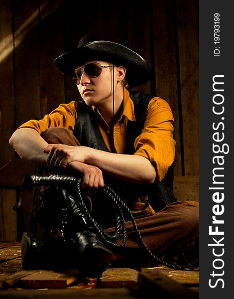 Cowboy with Black Leather Flogging Whip in his hand against wooden background