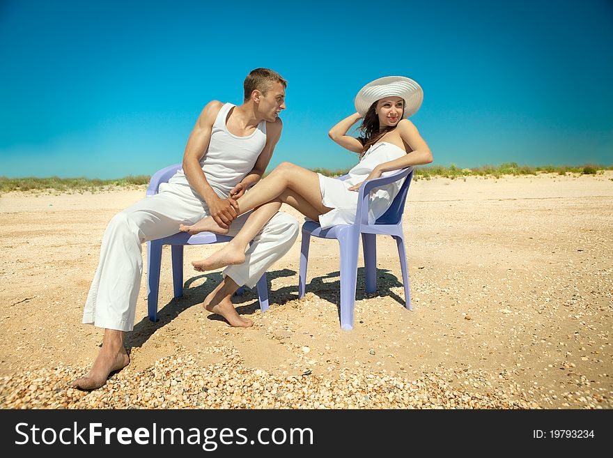 Happy romantic couple resting on beach in chairs lounge