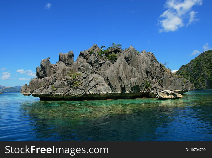 Mirrored water of lagoon with a lonely rock in Philippines