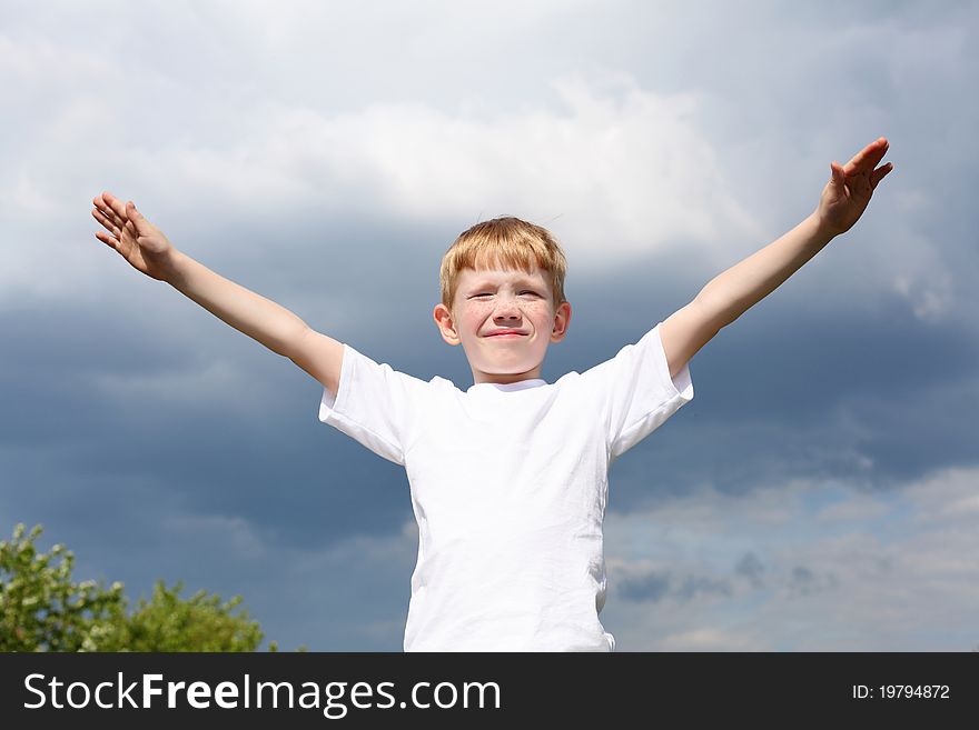 Carefree litlle boy outdoors embracing skies on lawn