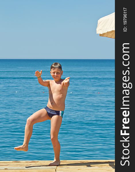 Boy standing on a pier on the background of the sea