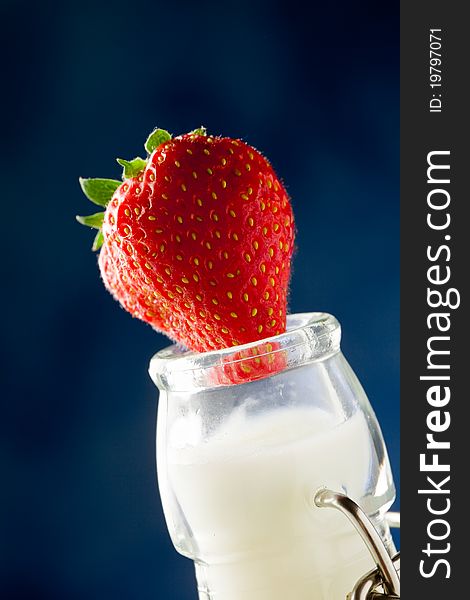 Photo of milk bottle with fresh red strawberry on it. Photo of milk bottle with fresh red strawberry on it