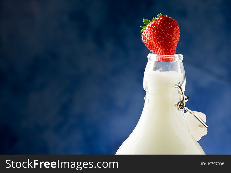 Photo of milk bottle with fresh red strawberry on it. Photo of milk bottle with fresh red strawberry on it