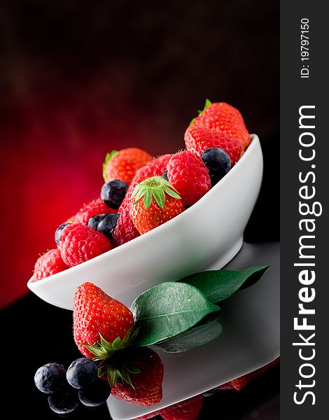 Photo of mixed fresh berries on red lighted background