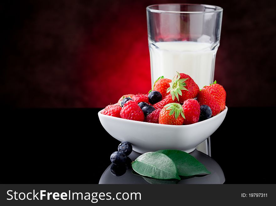 Photo of milk glass with berries on red lighted background. Photo of milk glass with berries on red lighted background