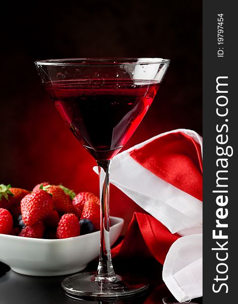 Photo of calyx with cocktail with berries on red lighted backgroud