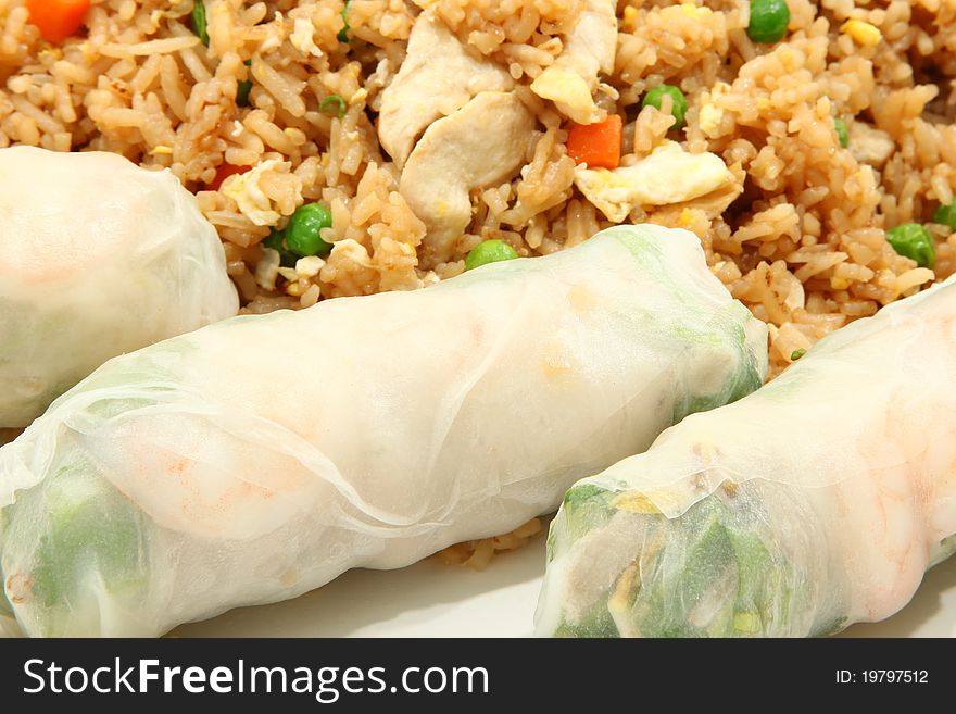 Three shrimp spring rolls on plate with chicken fried rice in background. Three shrimp spring rolls on plate with chicken fried rice in background.