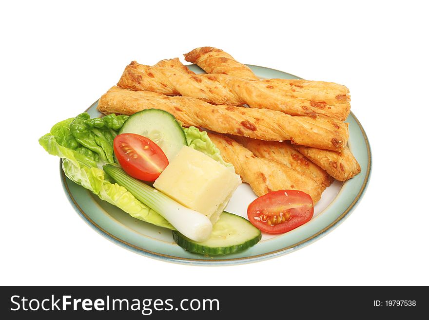 Cheese twists and salad garnish on a plate isolated against white