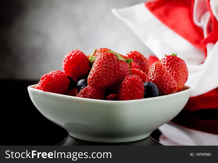 Photo of mixed fresh berries on grey lighted background