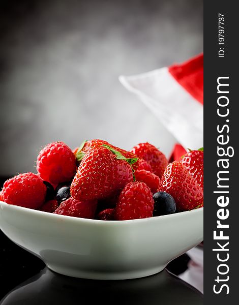 Photo of mixed fresh berries on grey lighted background