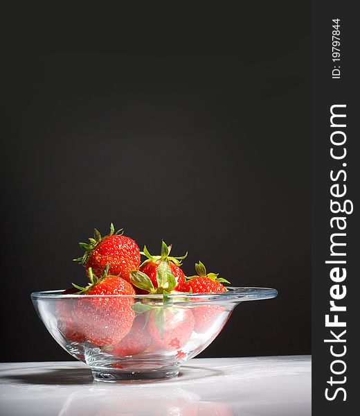 Tasty strawberries in a bowl on black background