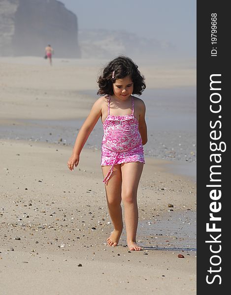 Little girl on the beach running in the coastline