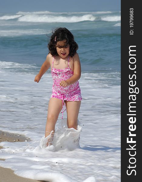 Little girl on the beach running in the coastline