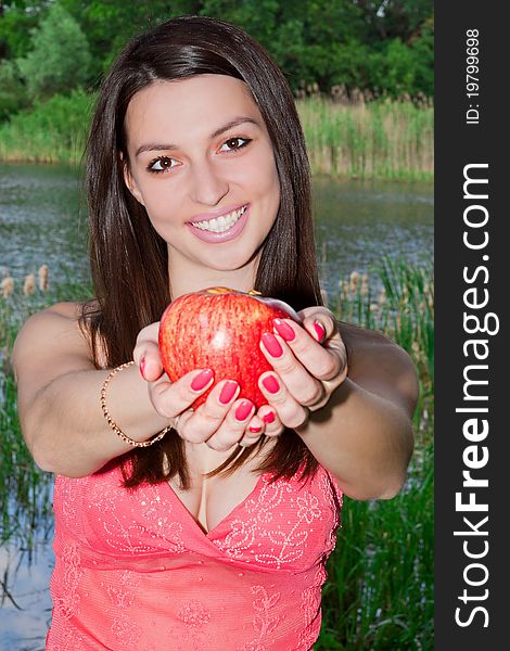 Young woman holding an apple in the park, smiling. Young woman holding an apple in the park, smiling