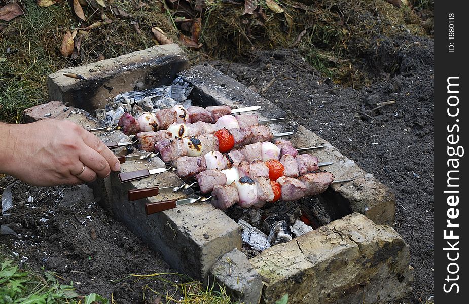 Hand and a meat fried at fire. Shashlik