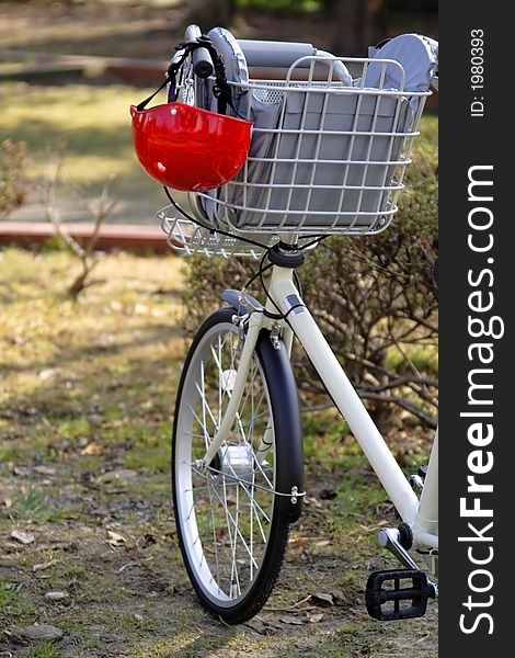 Image of a bicycle handlebar with a kid helmet hanging down in a park. Image of a bicycle handlebar with a kid helmet hanging down in a park.