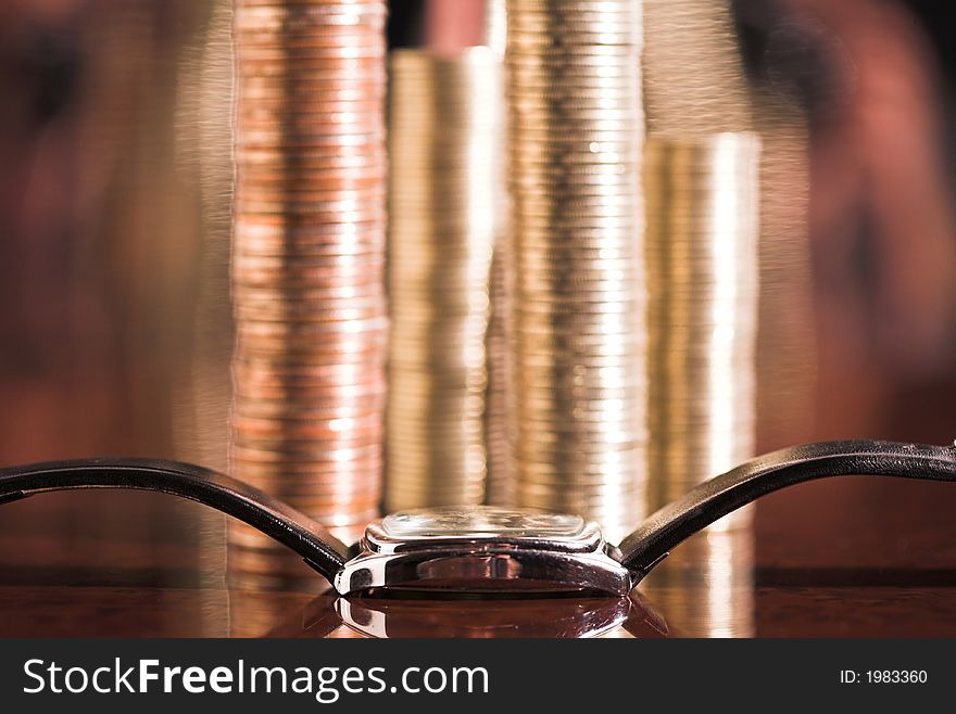 Set of coins and watch on a table, (studio, halogen light, curved mirror). Set of coins and watch on a table, (studio, halogen light, curved mirror).