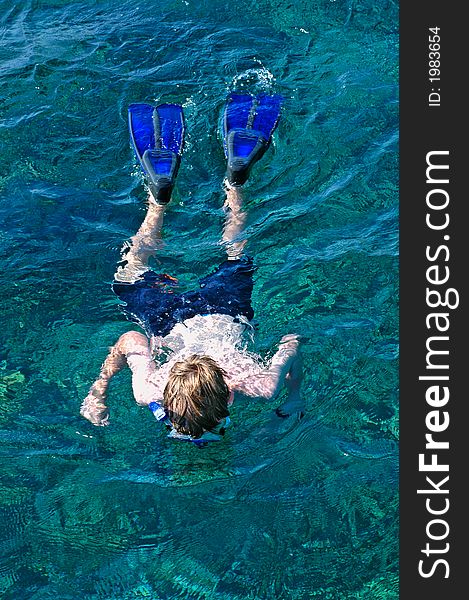 Boy snorkelling the clear ocean water with white sandd bottoms, beautiful colour fish and coral. Boy snorkelling the clear ocean water with white sandd bottoms, beautiful colour fish and coral