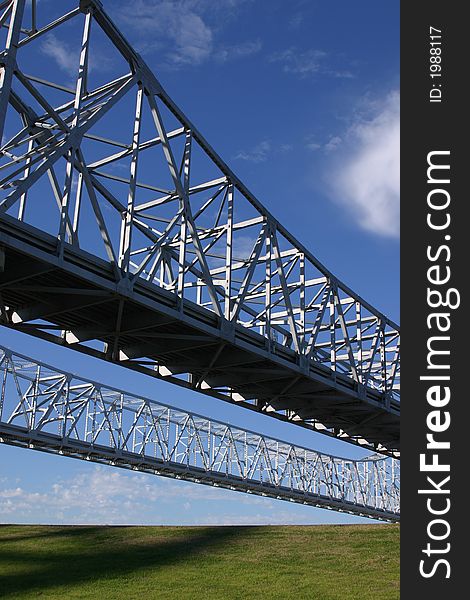Twin bridge spans of the Crescent City Connection in New Orleans cross above a levee.