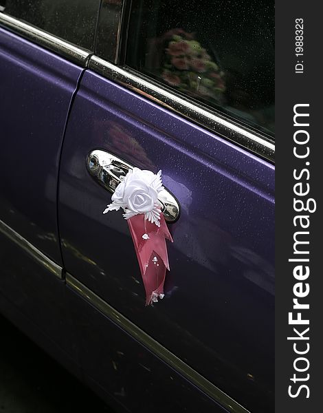 Flowers decorate a door of a limousine which has arrived for the groom and the bride