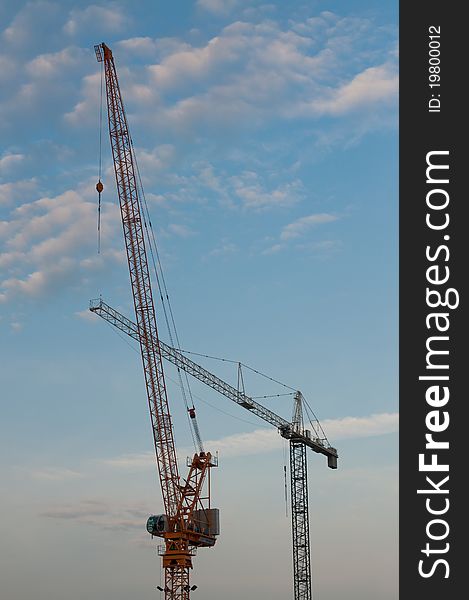 Two large cranes stand against a blue sky with clouds in the evening. Two large cranes stand against a blue sky with clouds in the evening.