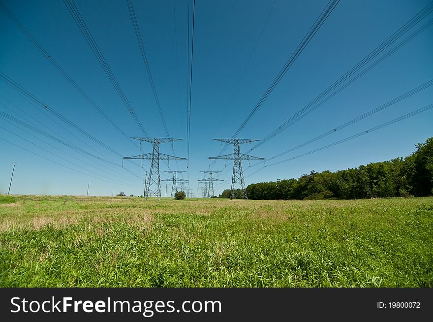 A long line of electrical transmission towers carrying high voltage lines. A long line of electrical transmission towers carrying high voltage lines.