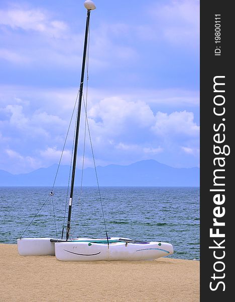 A small catamaran boat on beach sand, shown as enjoy holidy and beautiful sea view. A small catamaran boat on beach sand, shown as enjoy holidy and beautiful sea view.