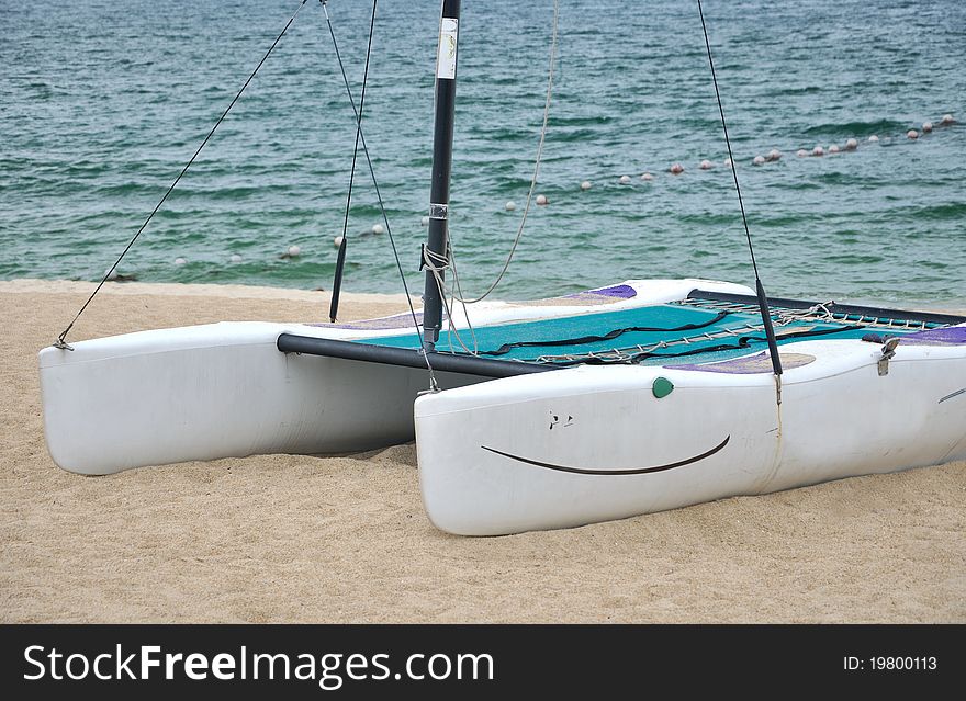 A small catamaran boat on beach sand, shown as enjoy holidy. A small catamaran boat on beach sand, shown as enjoy holidy.