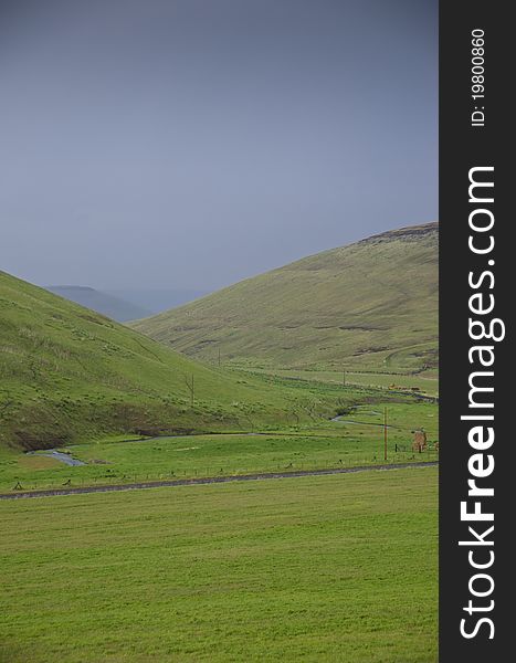 Green hills below storm clouds