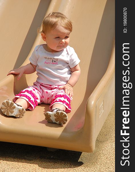 A toddler is playing on a slide and enjoying life on a warm sunny day at the park. A toddler is playing on a slide and enjoying life on a warm sunny day at the park.