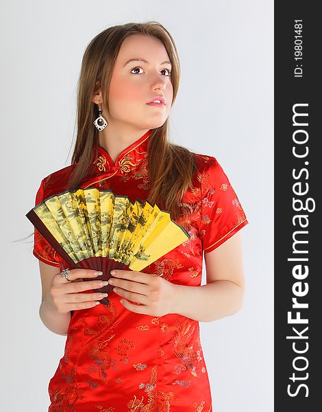 The beautiful young girl in a red Chinese dress with a yellow fan. The beautiful young girl in a red Chinese dress with a yellow fan