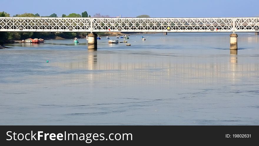 A metal bridge crossing a quiet river over small boats. A metal bridge crossing a quiet river over small boats
