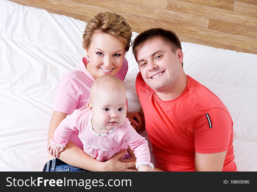 Lifestyle portrait of the Beautiful young happy family lying in bed at home - high angle